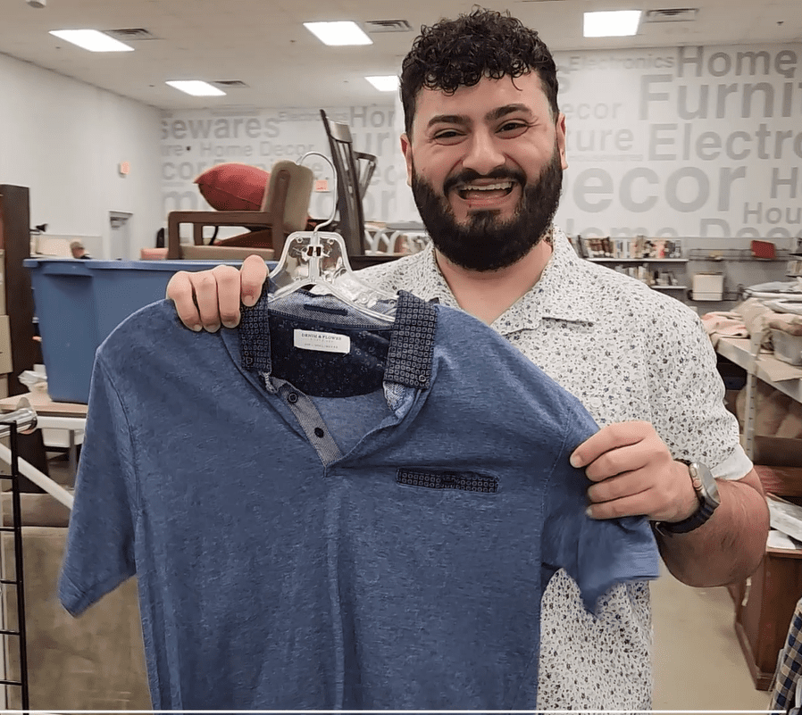 A person holding a blue shirt in Goodwill