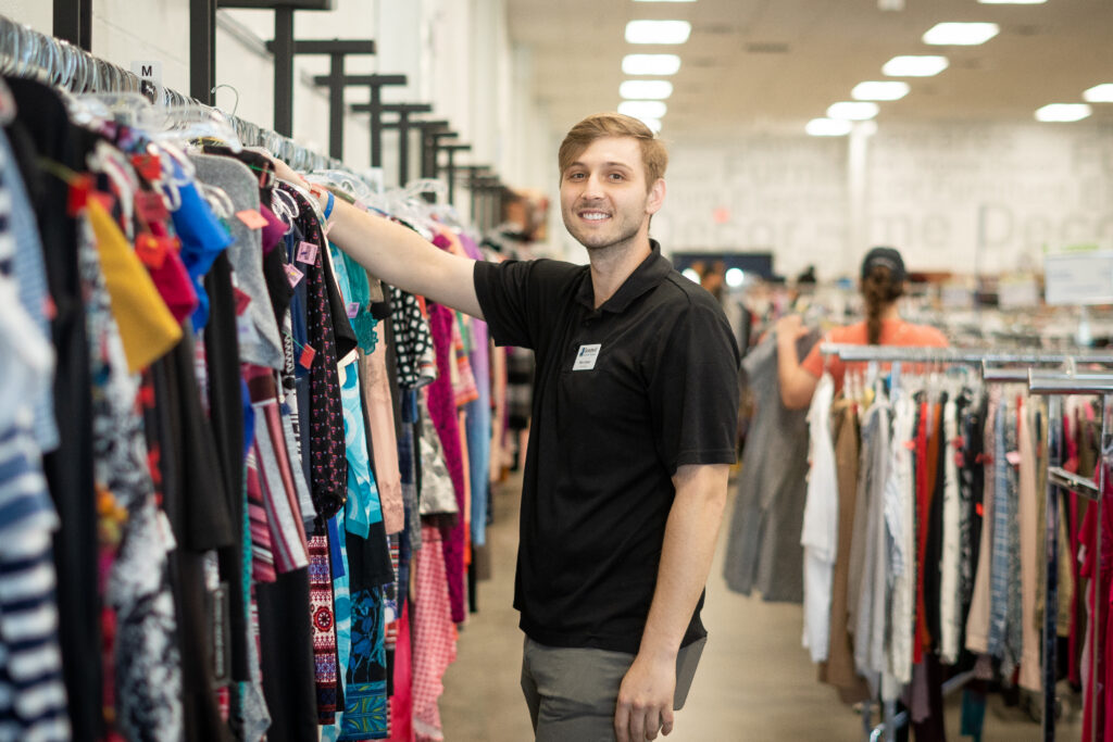 Goodwill employee hanging clothes