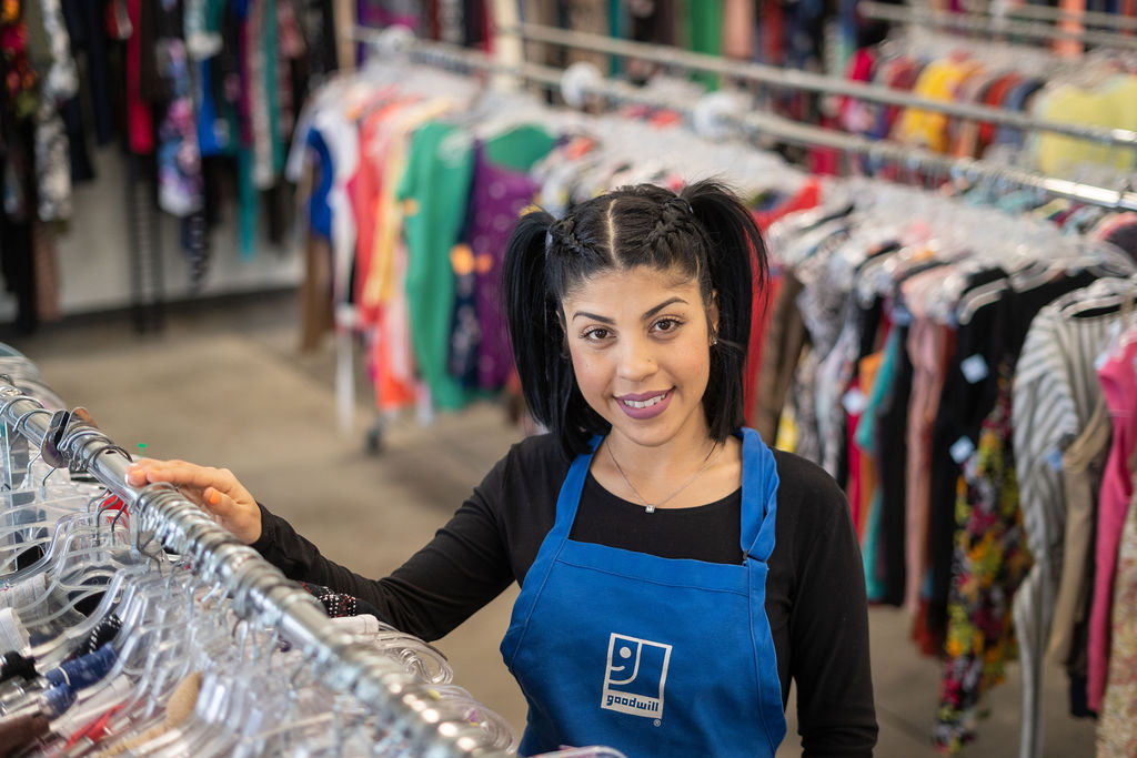 Goodwill employee hanging clothes