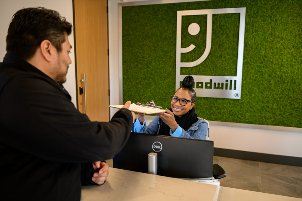 Goodwill employee passing a clipboard to a visitor